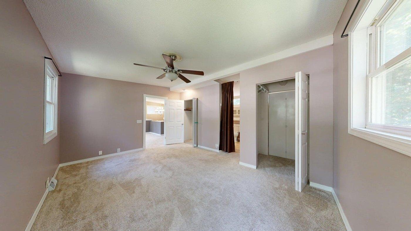 Before virtual staging: empty bedroom photo with carpet, window, closet, and doorway